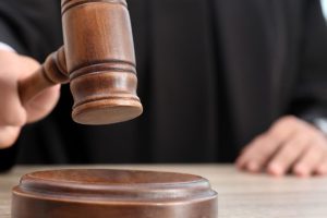 Judge-with-gavel-at-wooden-table-indoors-closeup.jpg
